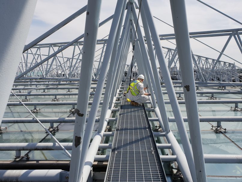 Man preparing paintwork at height with harness